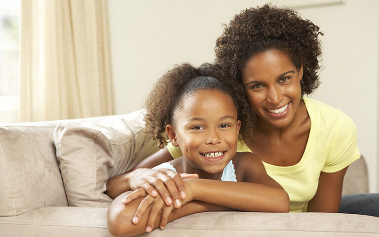 happy mother and daughter sitting on couch