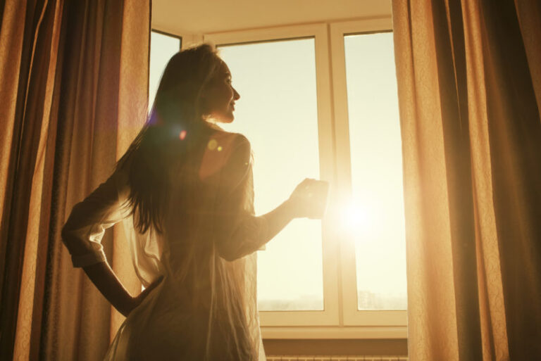 woman letting sunlight in room